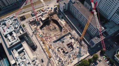 Construction workers building housing units or new skyscrapers between two buildings. Three cranes seen from aerial drone perspective. High quality 4k footage