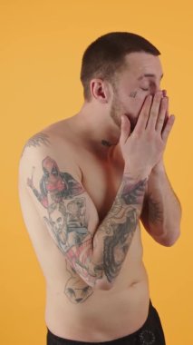 vertical video - 30s Caucasian man with tattoos folds arms and looks up isolated copy space studio shot medium shot . High quality 4k footage