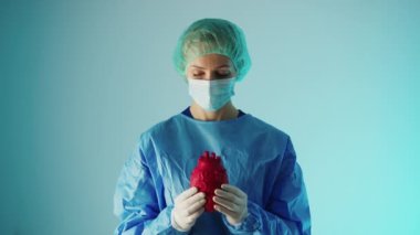young caucasian surgeon holding a 3d artifficial heart model and showing it to the camera, cardiovascular diseases prevention. High quality 4k footage