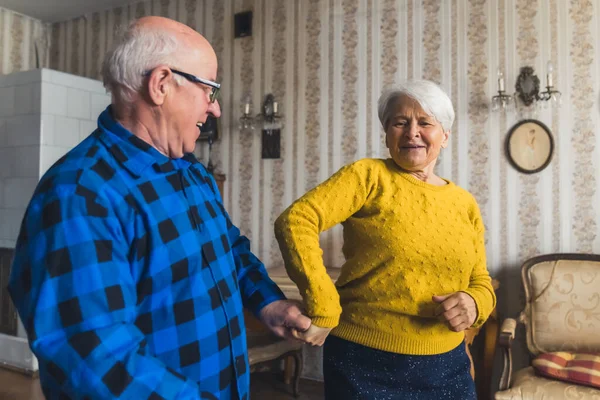 Joyful caucasian elderly woman dancing with her happy husband together in the living room of their own house. High quality photo