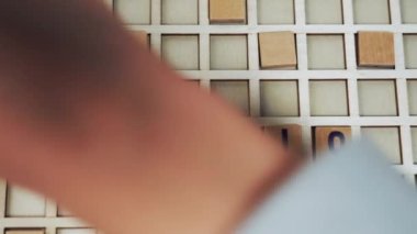 ILLUSION. Colourful square wooden letters on a white board seen from top view. Advertisement concept. High quality 4k footage