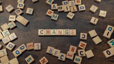 CHANGE. Scattered wooden square letter puzzles on a dark wooden table. Advertisement concept. High quality 4k footage