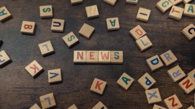 NEWS. Information and proper sources concept. Symbolic depiction of the news with the use of wooden square colourful letters. High quality 4k footage