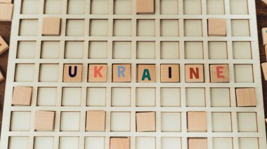 Square wooden colourful letters with the word UKRAINE on it. White wooden board. Anti-war concept. High quality photo