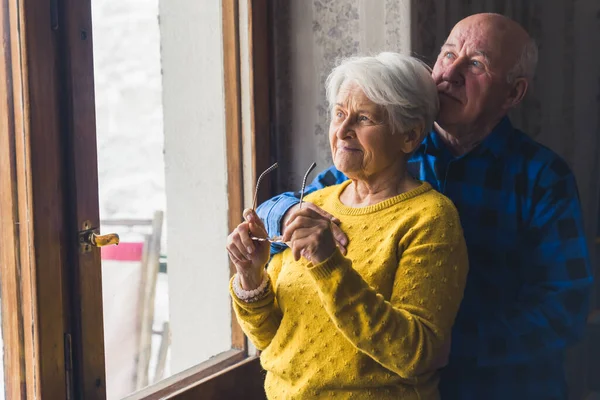 Portrait Elderly Couple Standing Looking Away Window Caring Husband Hugging — Stockfoto