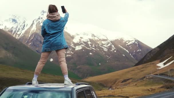 Дівчина Стоїть Даху Автомобіля Робить Селфі Горах Казбегі Джорджія Кадри — стокове відео