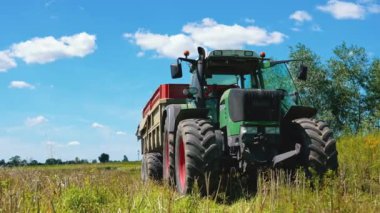 Rape Seed Harvesting. A big agricultural tractor with a yellow in a huge endless sunny field in a rural area. Transportation of oilseed rape crop after being harvested by combine harvester during