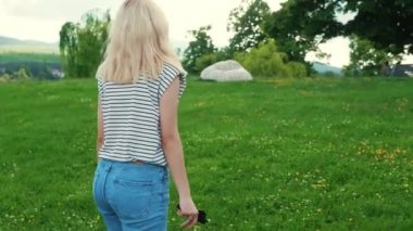 blond Caucasian girl walking in the beautiful green nature, medium shot. High quality 4k footage