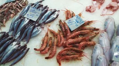 Kapani Market, one of the largest and most popular covered markets in Thessaloniki, Macedonia, Greece. Seafood counter with prices in Euros at Kapani covered market. Shops selling fresh raw fish