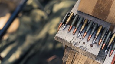 Close-up of rifle bullets on tape for machinegun stored on wooden table. Firing range. Focus on foreground. Horizontal shot. High quality photo