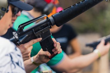 2022.08.07 Modlin, Poland - Group of people training how to operate guns. Firearm training at firing range. Safety gear. Close-up of submachine gun. Outdoor horizontal shot . High quality photo