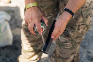 Close-up of gunsmith in camo clothing spraying barrel of gun. Gun maintenance. Repairing army equipment. Horizontal shot. High quality photo