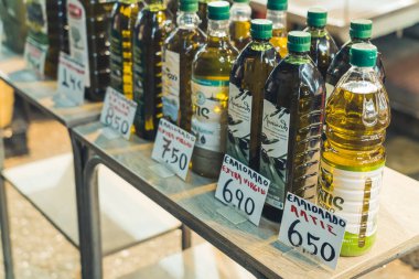 07.13.2022 Thessaloniki, Greece. Different kinds of pure Greek olive oil in plastic and glass transparent bottles with green caps standing on a display at the famous Kapani Market. High quality photo