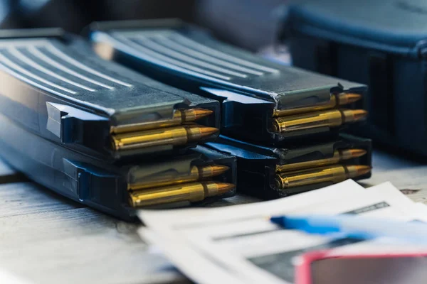 Close up of clips with nato bullets and documents. Selling and storing firearm equipment and ammunition. Horizontal shot. High quality photo