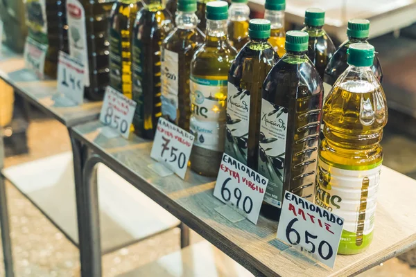 07.13.2022 Thessaloniki, Greece. Different kinds of pure Greek olive oil in plastic and glass transparent bottles with green caps standing on a display at the famous Kapani Market. High quality photo