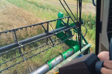 Blue-collar work concept. Unrecognizable caucasian farmer harvesting with the use of combine harvester. Operators perspective. High quality photo