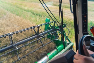 Combine harvester operators perspective during harvesting. Unrecognizable caucasian farmer driving an agricultural machine. High quality photo