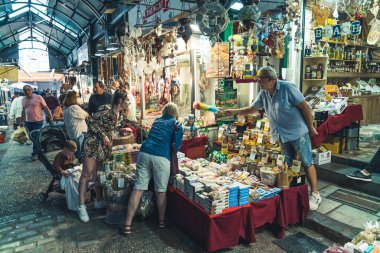 07.13.2022 Thessaloniki, Greece. Interaction between Greek male seller and customers at famous Kapani Market. People choosing ideal spices. High quality photo