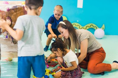 a teacher painting with her kids at nursery. High quality photo