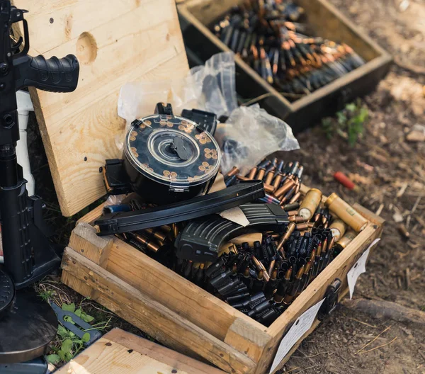 Square outdoor shot of two wooden boxes filled with ammunition and other accessories for firearm. Military concept. Day at shooting range. No people. High quality photo