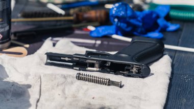 Handgun broken down into parts with exposed barrel at gunsmith workshop. Gun maintenance gear. Close-up horizontal shot. High quality photo