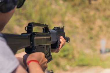 Unrecognizable man aiming shotgun practicing on outdoor firing range. Blurred background horizontal shot . High quality photo