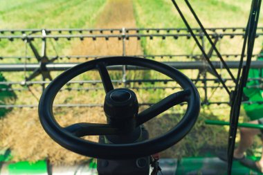 Black steering wheel of a combine harvester. Farmers perspective of harvesting process. Modern agriculture concept. High quality photo