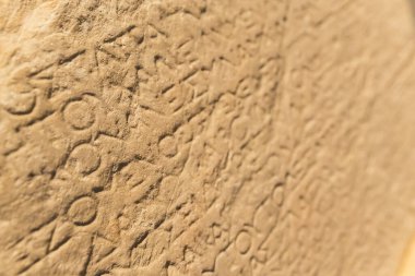 Greek language concept. Closeup shot of Greek alphabet words carved into a beige stone wall. High quality photo