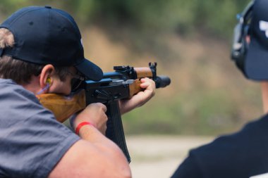 08.07.2022 Warsaw, Poland Competition at shooting range. Unrecognizable caucasian man in a black hat using a rifle. Blurred background. Unconventional hobby. High quality photo