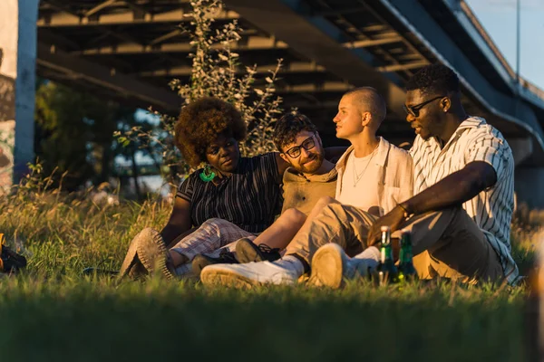 Positive Diverse Group Friends Sitting Together Blanket Grass Campfire Drinking — Stock fotografie