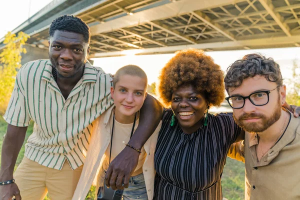 Multi-ethnic group of best old friends, who finally reunited after a long time separate living and studying in different countries, having a weekend picnic near the river. Taking pictures together