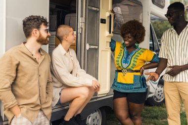 Summer camping trip. A multicultural group of good old friends talking, joking, laughing and enjoying spending time together in nature while living in their motorhome. High quality photo