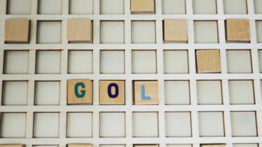 Short closeup clip showing a palm of an unrecognizable caucasian person putting wooden letters together creating the word GOLD. Wordplay concept. High quality 4k footage