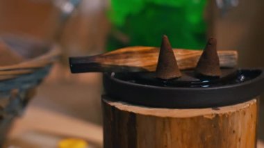 Closeup shot of two cones made of CBD hashish standing on a special incense plate with Palo Santo wood. Alternative ways of fighting with anxiety, stress, and much more. High quality 4k footage