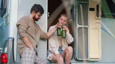 Cheers. Interracial group of cheerful people clinking beer bottles, having drinks to celebrate a special occasion inside their comfortable spacious camper van. Spending weekends together on a summer
