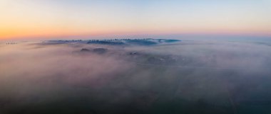Colorful sunrise and thick fog over vast farm fields of Roztocze Poland. Nature and agriculture. Wide horizontal shot. High quality photo