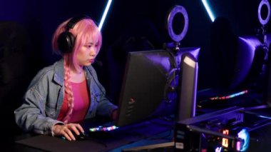 Asian girl with pink hair taking part in the cyber sport tournament, medium closeup. High quality 4k footage