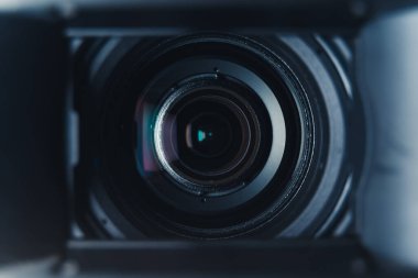 Close-up black professional camera lens with hood and color reflections. High quality photo