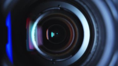 Close-up black professional camcorder transfocation zoom lens with hood and color reflections. High quality 4k footage