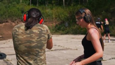 Caucasian man and woman wearing safety headphones training with submachine gun on firing range. Firearms training. Outdoor horizontal shot. High quality 4k footage