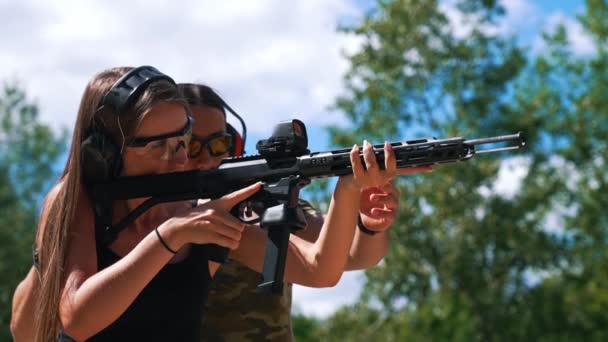 Bearded Man Camo Shirt Watching Woman Aiming Submachine Gun Safety — Stok Video