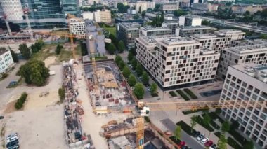 Birdseye view of construction site with cranes next to residential areas in the center of Warsaw Poland. Streets sidewalks and trees. Horizontal. High quality 4k footage