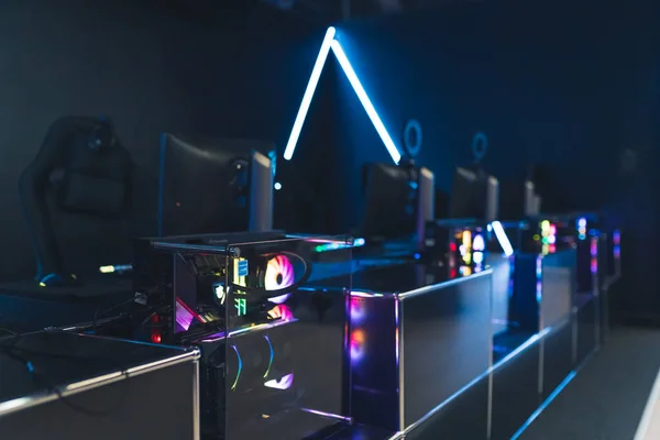 Monitors and computers in trapnsparent cases with rainbow glowing fans. Professional gaming setup. Blue neon lights. Horizontal shot. High quality photo