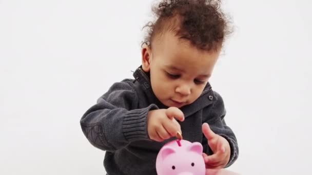 Cute Little Boy Putting Coin Piggy Bank Medium Closeup White — ストック動画