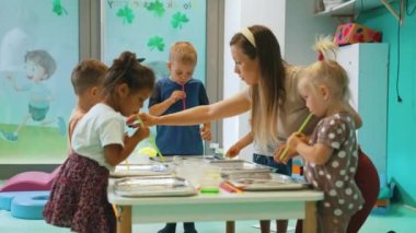 Multi-cultural nursery school. Toddlers playing with striped straws and milk painting, using nontoxic food coloring for colors. Creative kids activity for using their senses and brain development