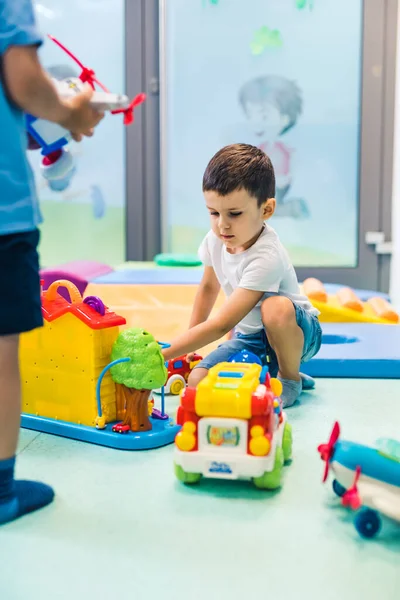 Imagination and creative thinking development. Language and social skills. Toddler playing with colorful plastic toys and colorful car in a nursery school playroom. High quality photo