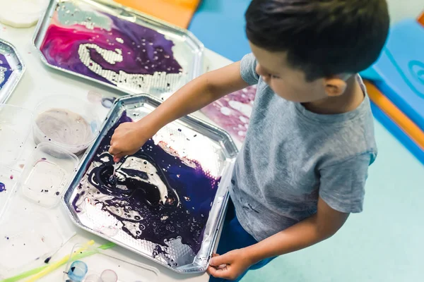 Sensory play for brain development at nursery school. Toddlers playing with striped straws and milk painting, using nontoxic food coloring for colors. Creative kids activity for using their senses