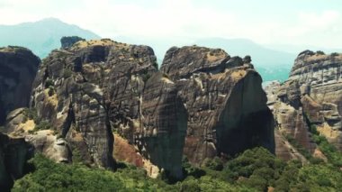 Stunning natural rock formations of Meteora, Greece covered halfway with green trees and bushes. Clear sky. High quality 4k footage