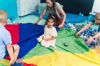 Sensory playtime at the nursery school. Toddlers with their teacher playing with ball-pit balls. Learn and develop through play. High quality photo