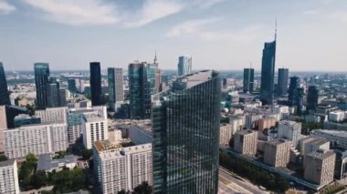 Glass-covered high-rise building in housing estate in the center of Warsaw Poland with skyscrapers in the background. Horizontal drone shot. High quality 4k footage